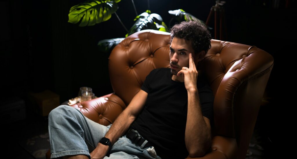 male model posing while sitting in a leather armchair